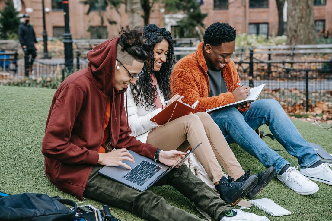 Group of students studying and learning together outdoors with their laptops and books. A productive and collaborative environment for education.