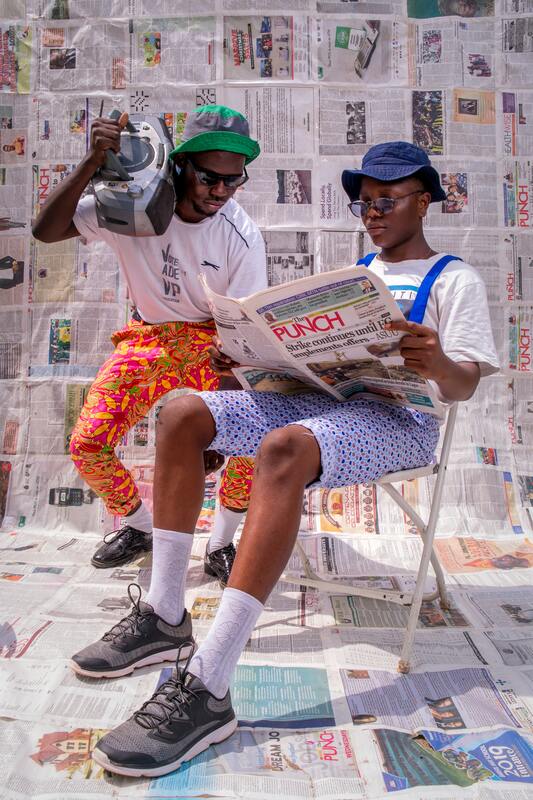 wo vintage hip-hop enthusiasts check the news while blasting tunes from their boombox.